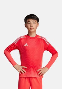 Rotes langärmliges Sportshirt mit einem strukturierten Farbverlauf-Design, weißen Schulterstreifen und einem Adidas-Logo auf der Brust.