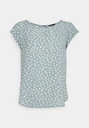 Krótka bluzka z krótkim rękawem w jasnym zielonym kolorze z nieregularnymi białymi kropkami, okrągłym dekoltem i luźnym krojem.