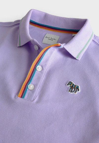 Lila polotröja i en texturerad tyg, med en flerfärgad randig krage, vita knappar och en liten broderad zebra-detalj.