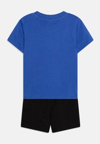 T-shirt in cotone blu con collo rotondo e maniche corte, abbinato a pantaloni corti in cotone neri. Design semplice, senza motivi o decorazioni.