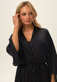 Black satin kimono-style robe with wide sleeves and a self-tie belt. Smooth texture with a wrap design, ideal for loungewear or layering.