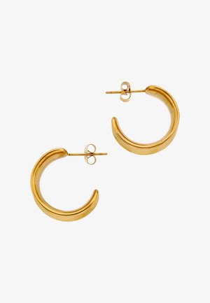 Małe, grube złote kolczyki w kształcie koła z zapięciami na sztyft, ułożone obok siebie na białym tle.