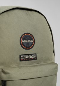 Zaino in tessuto verde con toppe in rilievo del marchio in nero e arancione, con una finitura texturizzata e un design a pattina pieghevole.