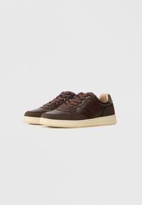 Sneakers in pelle marrone con accenti in suede, suola in gomma crema, punta rotonda, dettagli cuciti e logo di lato.
