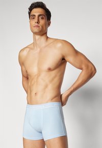 Hellblaue Baumwollboxershorts mit einem weißen elastischen Bund, auf dem der Markenname "JACK & JONES" in einem wiederholenden Muster zu sehen ist.