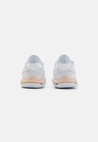 Pantofi sport de culoare albastru deschis, cu un strat din plasă, călcâi căptușit, talpă albă și accente bej pe partea inferioară. Vedere din spate evidențiind detaliile designului.