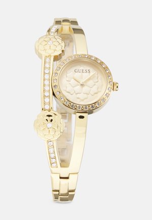Orologio da polso dorato con cassa rotonda, lancette dorate, accenti floreali e decorato con cristalli trasparenti lungo il bracciale.