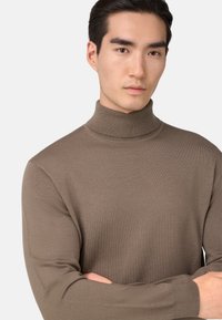 Hnedý rolák vyrobený z rebrovaného materiálu, s vysokým golierom a dlhými rukávmi, s priliehavým strihom.