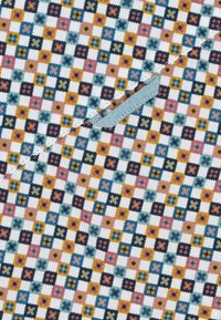 Textiel met een repetitief bloemmotief in roze, geel, zwart en blauw, tegen een witte achtergrond met een lichterblauwe accent.