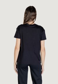 Camiseta negra de manga corta hecha de algodón suave, con cuello redondo y un corte relajado, con un diseño liso en la parte trasera y sin patrones visibles.
