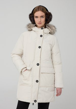 Parka bianca imbottita con cappuccio in pelliccia sintetica, grandi tasche frontali, bottoni neri e una fodera calda, abbinata a cuffie rotonde scure.