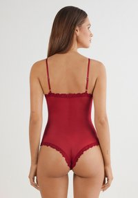 Roter Body mit verstellbaren Trägern, Spitzenbesatz am Halsausschnitt und an den Beinausschnitten sowie einer eleganten, glatten Textur.