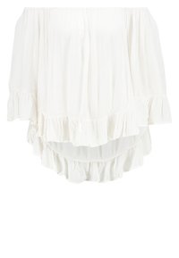 Vit av-axlar topp tillverkad av lätt tyg, med tre volanger längs fållen och en krinklad textur.