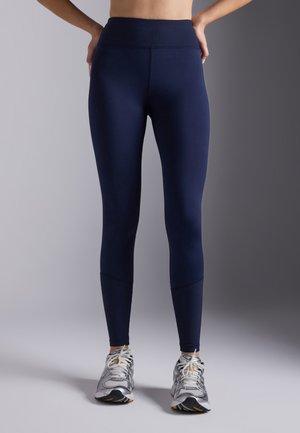 Navy leggings with a high ribbed waistband, smooth texture, and fitted design. Features a subtle seam detail at the ankles.