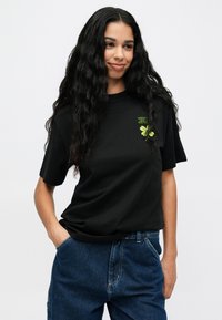 Must kottont-särgid, lühikeste varrukatega, lõdva lõikega ja rohelise tikandiga lehega kaunistatud rinnal. Ükslane selg ja ümar kaelus.