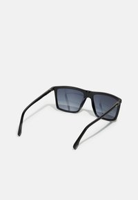 Black sunglasses with a rectangular frame, gray-tinted lenses, and thin arms featuring a subtle metallic accent at the hinges.