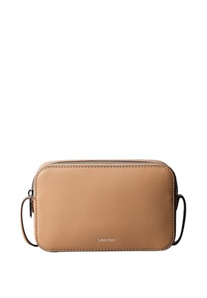 Pochette bracelet rectangulaire en cuir fauve avec fermeture éclair argentée sur le dessus et logo Calvin Klein centré à l'avant.