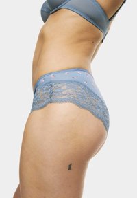 Modré kalhotky s krajkovým lemem, zdobené květinovými akcenty, vyrobené z měkké tkaniny s hladkým povrchem a nízkým střihem.