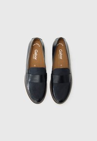 Chaussures noires en cuir à enfiler avec une finition lisse, dotées d'une large bande à l'avant, d'une semelle intérieure perforée et d'une semelle en caoutchouc marron.
