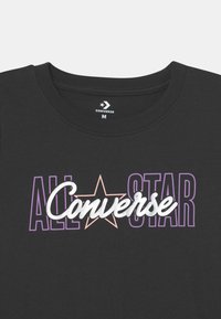 Czarny t-shirt bawełniany z napisem "ALL STAR" i "Converse" w kolorach fioletowym, srebrnym i różowym, z gwiezdnym akcentem na środku.