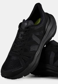 Černé sportovní boty s prodyšným síťovaným svrškem, texturedními detaily a polstrovanou černou podrážkou s mírným zvýšením paty.