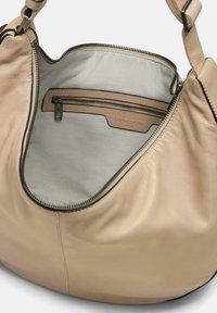 Borsa in pelle beige morbido con una texture liscia, dotata di un interno in tessuto grigio, una tasca con zip e dettagli in zip neri.