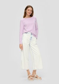 Lilafarbene Langarmbluse kombiniert mit weißen weit geschnittenen Jeans mit blauer Stickerei und beigen Riemchensandalen, vor einem neutralen Hintergrund präsentiert.