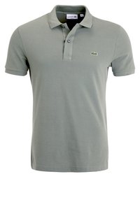 Polo vert clair en tissu texturé. Comprend une patte de boutonnage à trois boutons et un logo vert brodé sur la poitrine. Manches courtes.