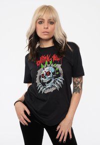 Black t-shirt made of cotton featuring a graphic design of a skull surrounded by spikes and colorful elements. Short sleeves, casual fit.