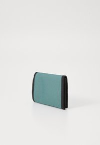 Cartera plegable de tela color teal con bordes de acento en negro. Forma rectangular, superficie texturizada, diseño ligero con costuras en contraste.