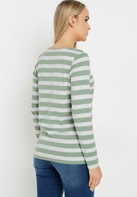 Grün-weißer gestreifter Langarmshirt aus weichem Stoff. Mit einem runden Ausschnitt und eng anliegenden Ärmeln, mit geradem Saum.