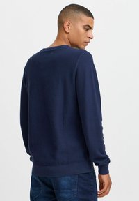 Mørkeblå teksturert genser med rund hals og ribbede mansjetter, med en vanlig passform. Stoffet ser mykt og lett ut.