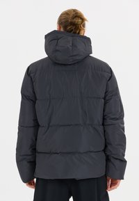 Mörkgrått quiltat puffjacka med huva, som har en mjuk och glänsande yta. Bakvyn visar horisontella sömdetaljer.