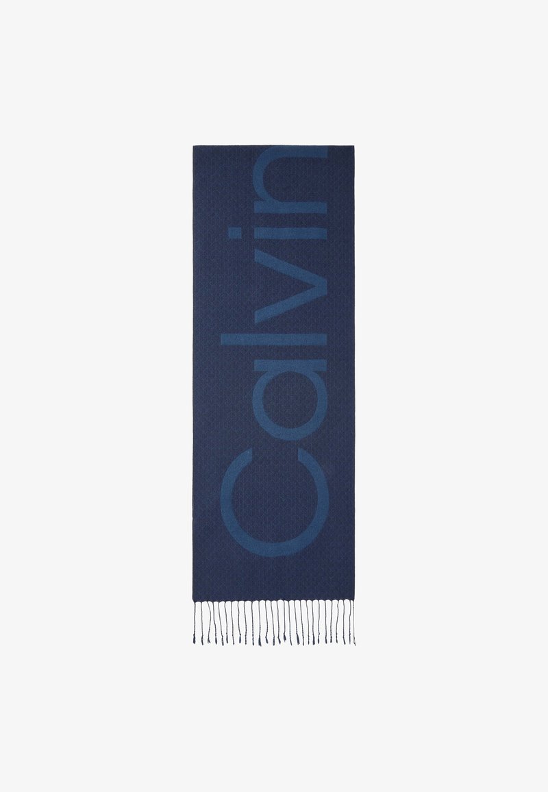 Écharpe rectangulaire bleu foncé avec un motif subtil et un grand texte "Calvin" vertical, finie avec des franges courtes à une extrémité.