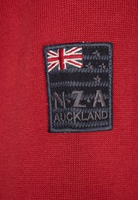 Morska naszywka z flagą Zjednoczonego Królestwa i gwiazdami, z napisem "NZ-A Auckland" wyszytym na czerwonym, dzianinowym materiale.
