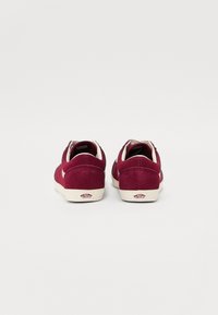 Adidași din suede cărămiziu, cu accente albe, vârf rotund, guler căptușit și detaliu cu logo pe călcâi. Design simplu și de tip low-top.