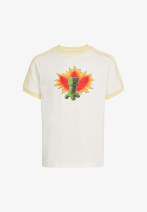 Camiseta blanca de manga corta con ribete amarillo pálido y gráfico de una criatura verde cuadrada frente a una forma de explosión naranja.