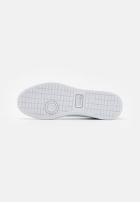 Semelle de chaussure blanche avec motif de bande de roulement en grille, détail circulaire près de la boule et zone rectangulaire pour logo avec texte "LACOSTE".