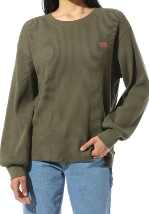 Camiseta de manga larga de textura waffle en verde oliva, con puños acanalados y cuello redondo, que presenta un pequeño logo naranja en el pecho.