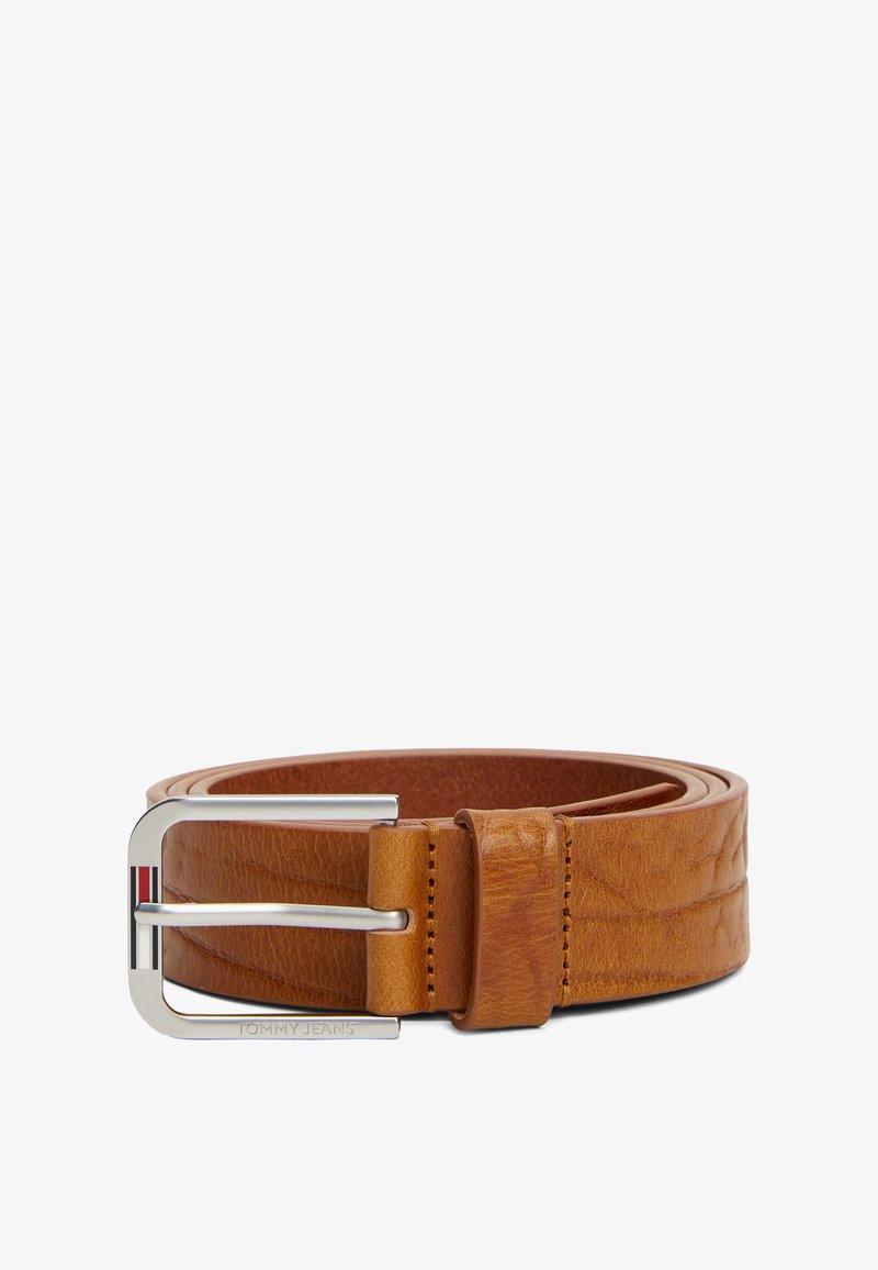 Ceinture en cuir beige avec une boucle en métal argenté. La boucle présente un détail en rayures rouge, blanc et bleu, ainsi qu'un marquage en relief. Texture lisse.