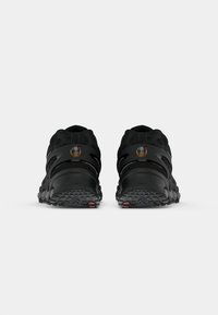 Um par de sapatilhas atléticas pretas viradas para trás com solas texturizadas e logótipos "Air Max" nos calcanhares, contra um fundo simples.
