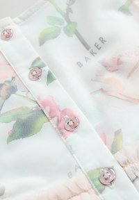 Blumen-Mesh-Stoff mit rosa und grünen Mustern, hellrosa Knöpfen und einem gerafften Saum. Der Text lautet "BAKER."