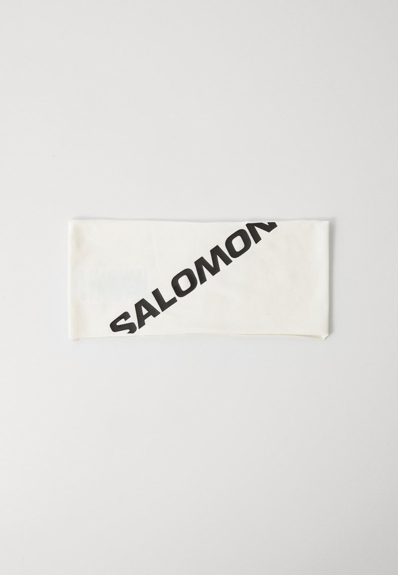 Fascia bianca in tessuto con il logo "SALOMON" in nero in diagonale sulla parte anteriore, su uno sfondo chiaro e semplice.