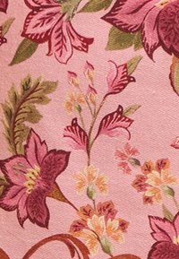 Floral fabric with a pink background, featuring large maroon and orange flowers, green leaves, and intricate detailing.