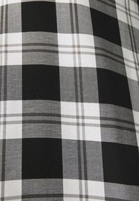 Svart och vit rutigt tyg med strukturerade, växlande rutor. Innehåller tunna grå linjer som korsar det rutig mönstret, texturerad yta.
