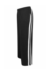 Un pantalon de survêtement noir avec une taille élastique, présentant deux bandes verticales blanches sur les côtés. Fabriqué en matériau doux et extensible.