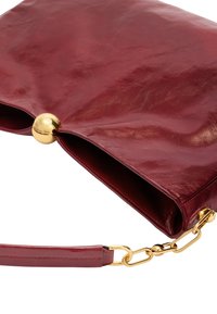 Clutch de cuero burdeos con una textura suave, que cuenta con un cierre redondo dorado y una correa de cadena desmontable. Forma rectangular con líneas limpias.