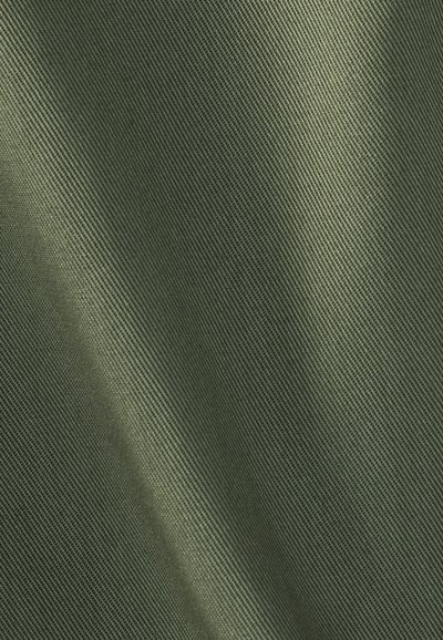 Κοντινή λήψη λείας, πυκνά υφασμένης ύφανσης σε ελιά πράσινο, με διαγώνια σκιά που αναδεικνύει την υφή και τις πτυχές.