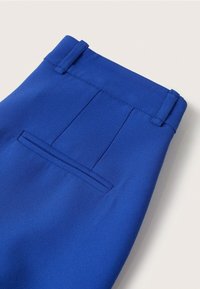 Pantalon en tissu bleu avec une ceinture structurée, une poche arrière et une texture lisse avec des plis sur mesure.
