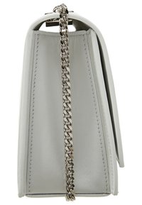 Valkoinen nahkalaukku hopeisella ketjuhihnalla, sivulta nähtynä, n äyttää sileän pinnan ja ompeleiden yksityiskohdat.